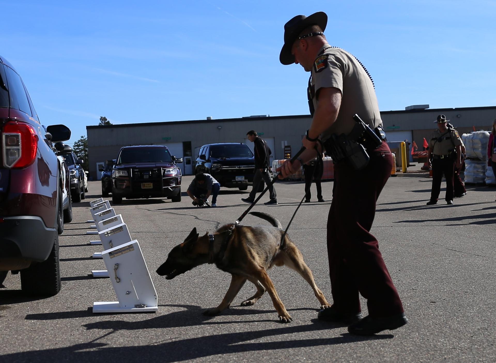 Trooper holding leash while k-9 sniffs a box